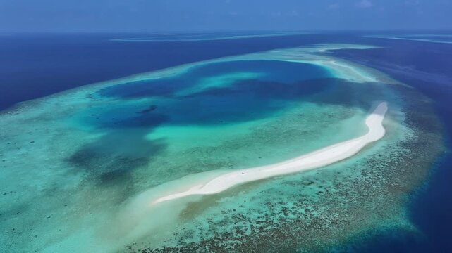 Aerial view of a pristine white sandbank surrounded by turquoise lagoons and vibrant coral reefs under a clear blue sky Kendhoo, Baa Atoll, Maldives.