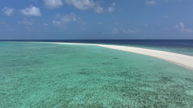 Aerial view of a pristine white sandbank stretching into crystal clear turquoise waters under a blue sky with scattered clouds in Kendhoo, Baa Atoll, Maldives.