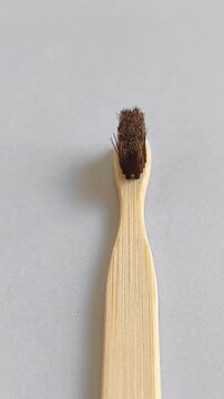 A bamboo toothbrush is filmed on a light gray studio background while the camera slowly pans from the handle to the bristles during a product video session to showcase sustainable oral care, natural m