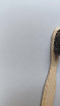 A camera movement transitions from a plastic toothbrush to a bamboo toothbrush, showing the heads and bristles of both products from the front during a studio video session on a neutral background to 
