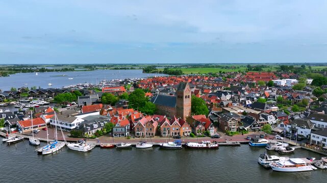 Aerial view of the historic town of Grou with red-roofed houses, the St. Piter's Church tower, and boats moored in the marina along the waterfront Grou, Friesland, Netherlands.
