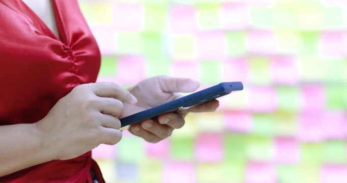 Woman using or typing messages on smartphone with colorful sticky notes background, Meeting, Planning, Touchscreen interaction, communication, productivity and modern digital lifestyle, close-up