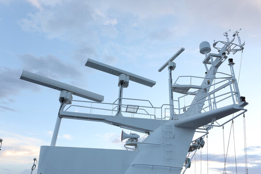 White cruise ship mast with marine radar antennas and satellite communication domes.