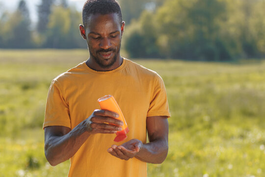 Man applies sunscreen lotion on a sunny summer day while enjoying outdoor activities for skin safety and sun protection.