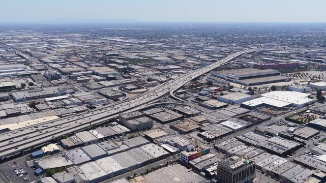 Elevated tripod perspective of vast industrial district panorama showing Interstate highway exchange with busy traffic and buildings sprawling across Los Angeles
