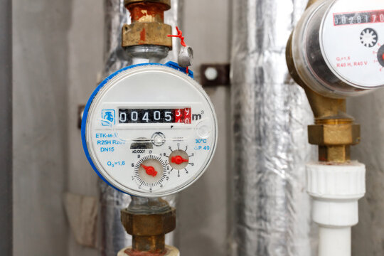 Water meters counter on pipes inside residential utility room infrastructure or bathroom plumbing pipeline maintenance, closeup view of domestic water supply measuring control systems equipment