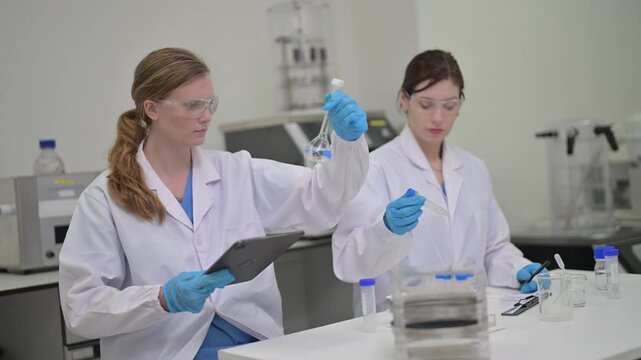 Researchers conduct tests in a laboratory with tablets and glassware
