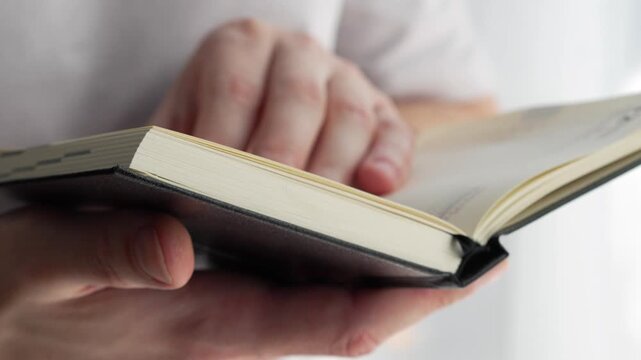 Paper pages in a notebook. A businessman holds a compact paper notebook with a bookmark in his hands.