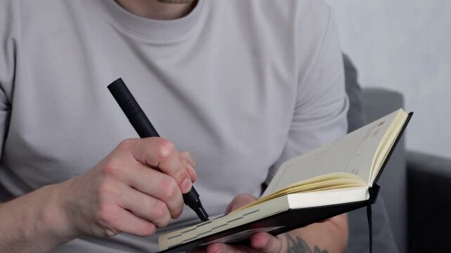A copywriter holds a notebook and pen.
Keeping a diary, handwriting information in a notebook.