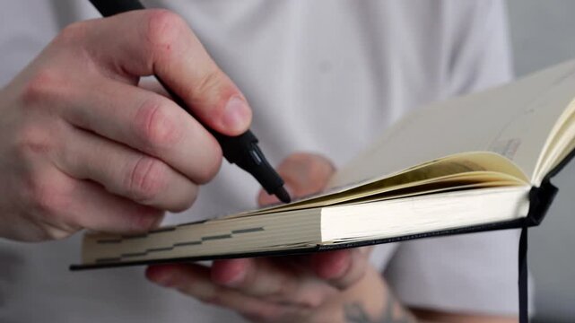 A copywriter holds a notebook and pen.
Keeping a diary, handwriting information in a notebook.