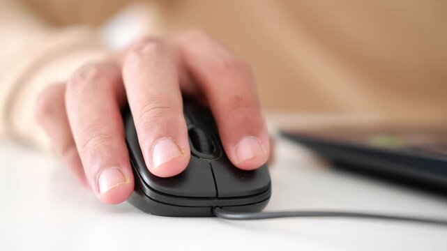 Man hand holding wired black computer mouse clicking buttons and scrolling wheel at desk