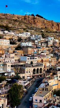Aerial vertical footage of Mardin Castle overlooking the ancient stone city of Mardin, T&uuml;rkiye. Historic architecture, cultural heritage, panoramic cityscape, and stunning Middle Eastern atmosphere ca
