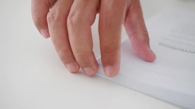 Finger folding page corner to make dog-ear bookmark before closing book on table