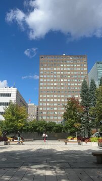 Sapporo, Japan on 25 September 2025: a bright afternoon in the city, with office buildings rising behind a small park filled with greenery. people can be seen walking, sitting, and spending time outdo