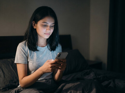 16 year old indian teenage girl using smartphone at night in bedroom representing social media addiction screen time insomnia online communication and digital wellness awareness