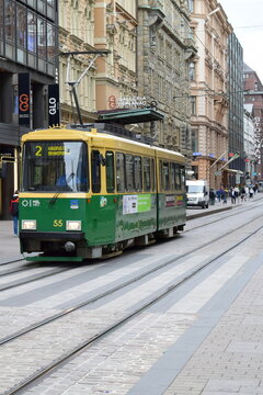 Traditional green and yellow Valmet tram operated by HSL moving on tracks on a historic city street. Helsinki, Finland, September 2015.
