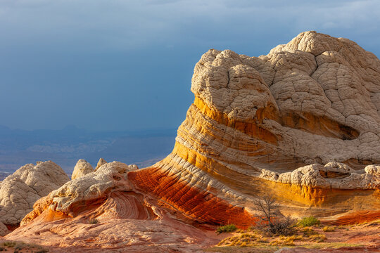 View of the unique sandstone formations of White Pocket with swirling orange and white rock textures under a dramatic stormy sky Coconino County, Arizona, United States.