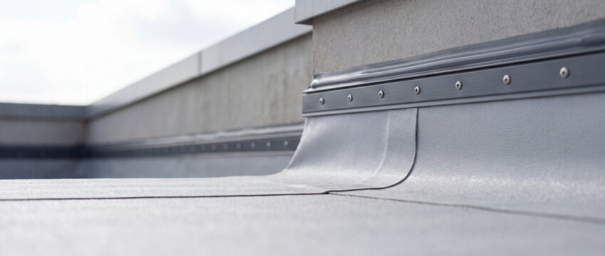 Flat commercial roof showing waterproof membrane and metal flashing at the parapet, highlighting roofing detail, construction finish, weatherproofing and modern building maintenance.
