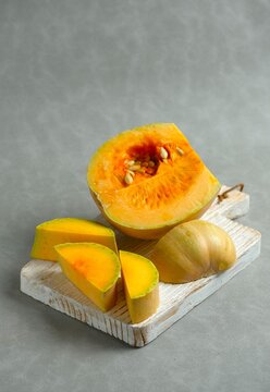 Chopped butternut squash pieces (Cucurbita moschata), also known as butternut pumpkin or labu madu, cut  on a gray background.