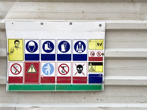 View of a construction safety sign board with various PPE icons mounted on a corrugated metal wall in Beylikduzu, Istanbul, Turkiye.