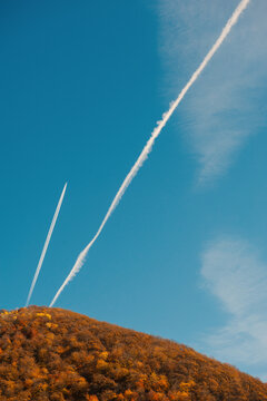 Airplane contrails cut sky creating airy dynamic geometry