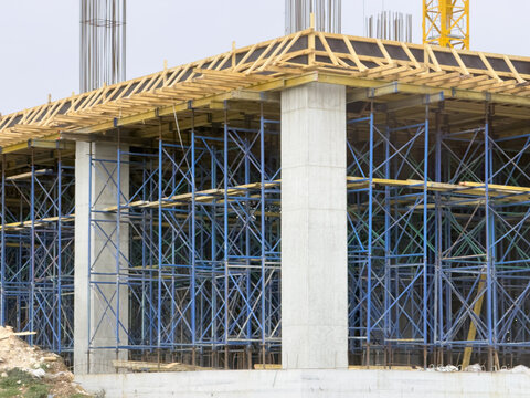 View of concrete pillars and blue scaffolding at a building construction site with wooden formwork Beylikduzu, Istanbul, Turkey.