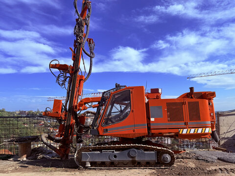 View of a large orange hydraulic drilling rig operating on a construction site under a blue sky with light clouds Beylikduzu, Istanbul, Turkiye.