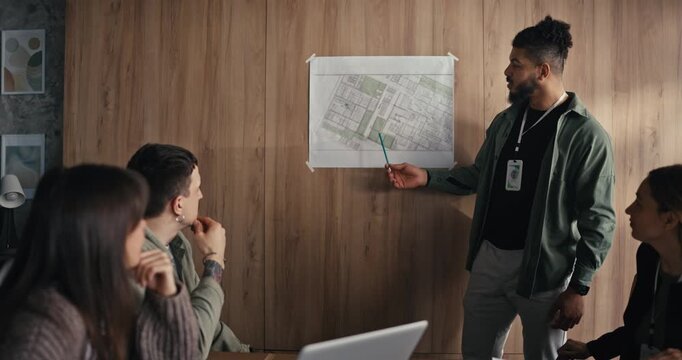 Group of people review a map while discussing plans. They use laptops and take notes