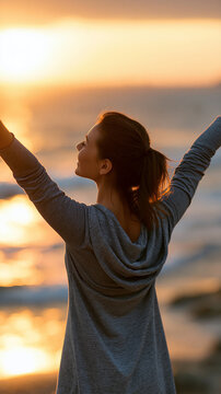 Happy woman with arms raised wide open enjoying freedom at the beach at sunset, wellness success and travel concept, positive outdoor lifestyle, faceless, back view, defocused