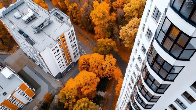Aerial view of modern apartment buildings surrounded by vibrant autumn trees.