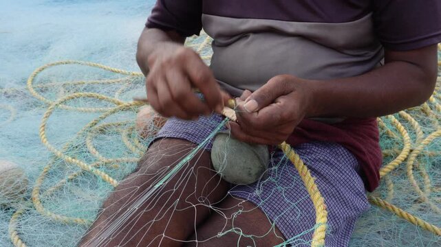 Person Repairing Fishing Net with Wooden Needle and Threads