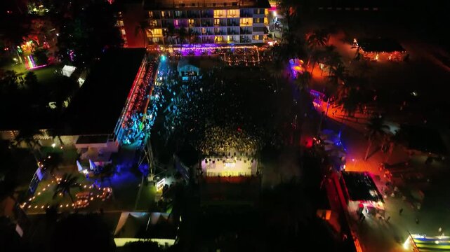Aerial view of a beach party festival with laser light show and crowd at night during spring break in Acapulco