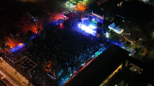 Aerial view of a beach party festival with laser light show and crowd at night during spring break in Acapulco