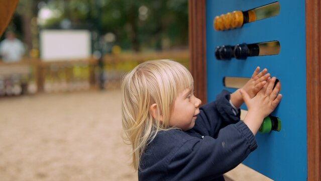 Brighthaired kid examines tactile shapes during outdoor activity
