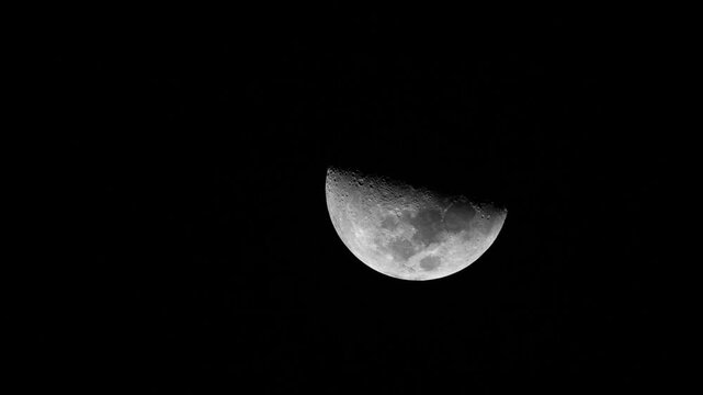 Timelapse of a half moon moving across a dark night sky, revealing detailed craters and lunar surface. Shot in 4K in Mauritius. Perfect for science, space, and nature projects.