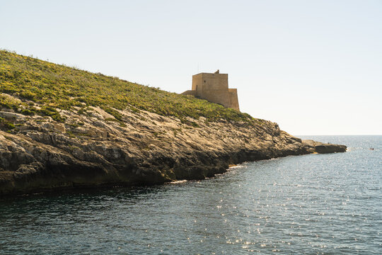 View of the historic Xlendi Tower standing on a rugged limestone cliff overlooking the Mediterranean Sea in Zebbug, Gozo Region, Malta.