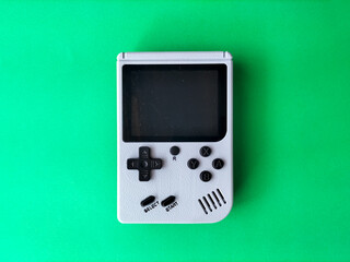 Retro handheld gaming console on a green background. © asep