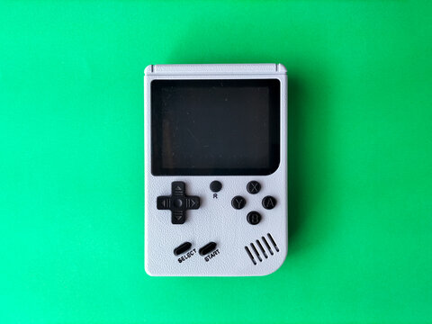 Retro handheld gaming console on a green background.