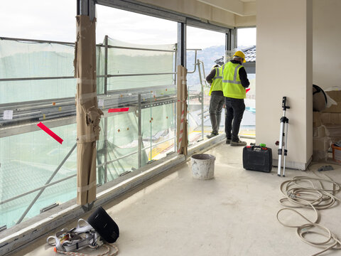 View of construction workers in yellow vests and hard hats working inside a building under renovation with scaffolding visible through large windows Avcilar, Istanbul, Turkiye.