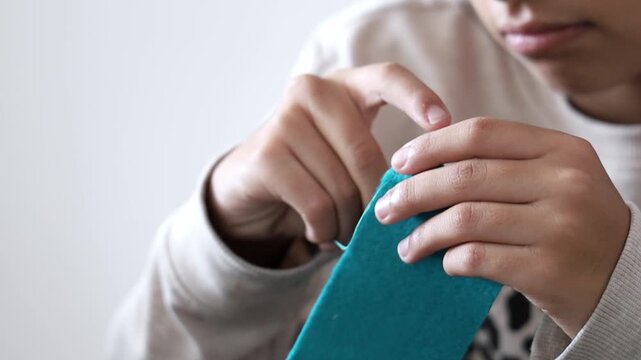 Happy Teenager Girl Learning To Sew With Needle And Thread At Home