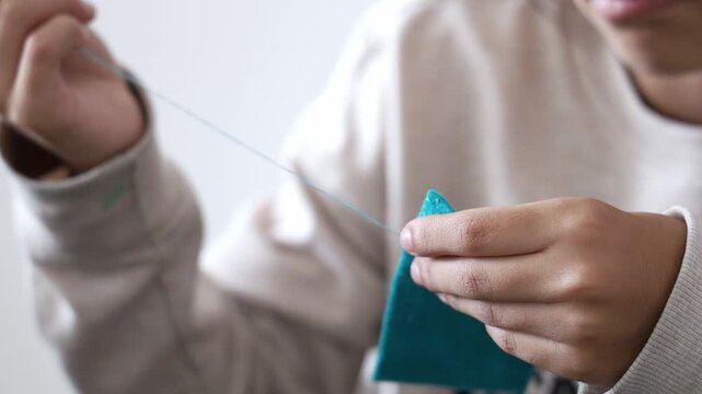 Happy Teenager Girl Learning To Sew With Needle And Thread At Home