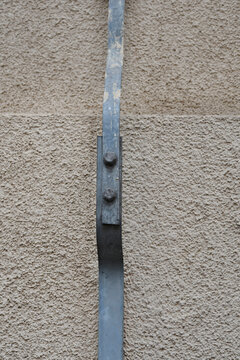 Close up view of a flat metal earthing conductor bolted together as part of a lightning protection system on an exterior wall.