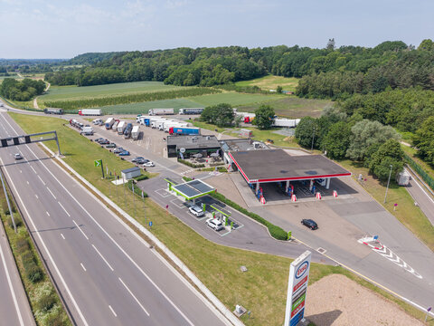 30 May 2026, Rotselaar, Belgium. Aerial drone view of highway service station with fuel pumps, EV charging infrastructure and parked trucks along E314