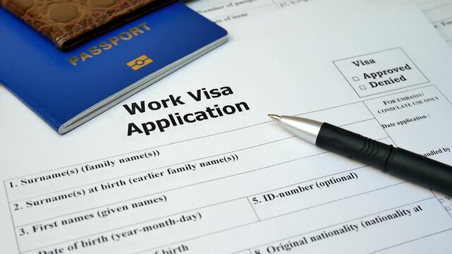 Close-up shot of a "Work Visa Application" form on a desk with a pen, blue passport, and smartphone, emphasizing the immigration process, global mobility, and international employment.
