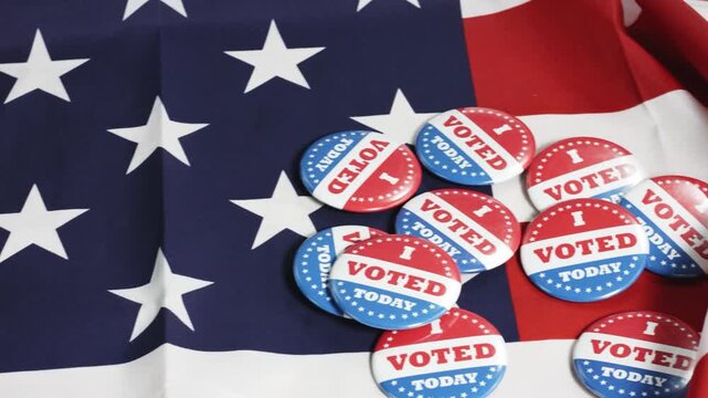 Close-up of a vibrant american flag draped with multiple "I voted today" buttons, symbolizing civic duty, patriotism, and the importance of democratic participation in elections.