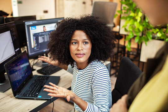 Woman explaining software at multi monitor workstation in modern office