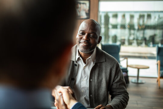 Business handshake with smiling man in modern cafe