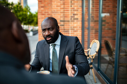 Businessman having serious discussion with colleague at outdoor cafe