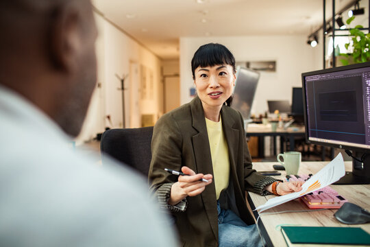 Creative professional discussing project with colleague in modern office