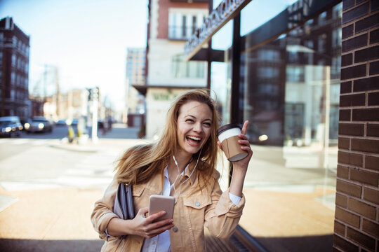 Smiling young woman with coffee on city street